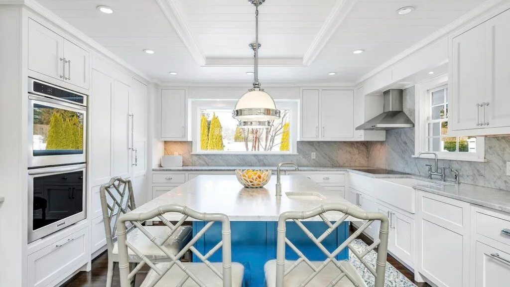 A bright white kitchen with a central island and counter seating.