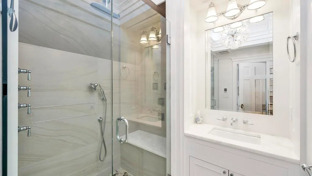 A bright bathroom with a glass shower and a white vanity beneath a large mirror.