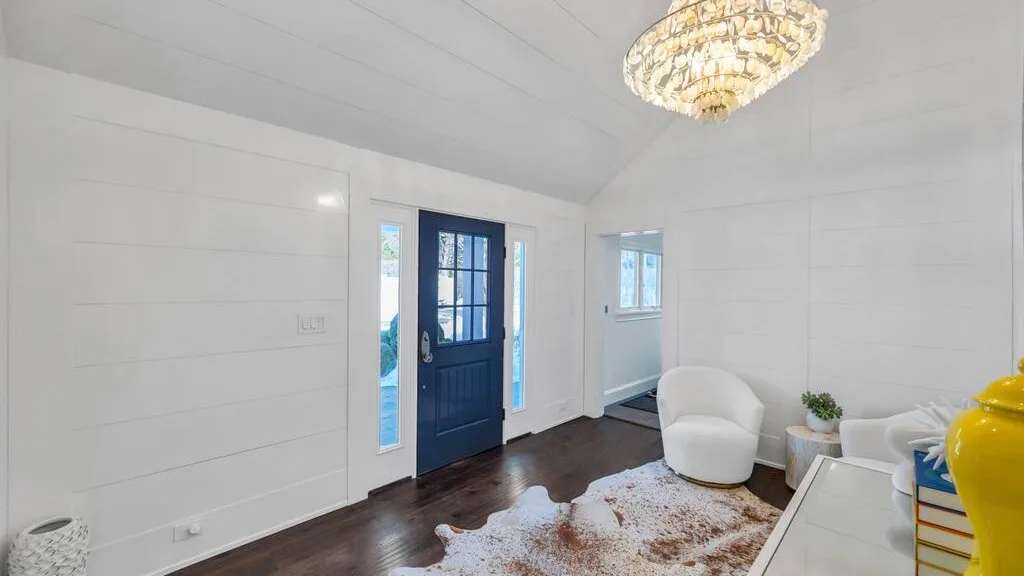A bright living room with a blue door and white seating.