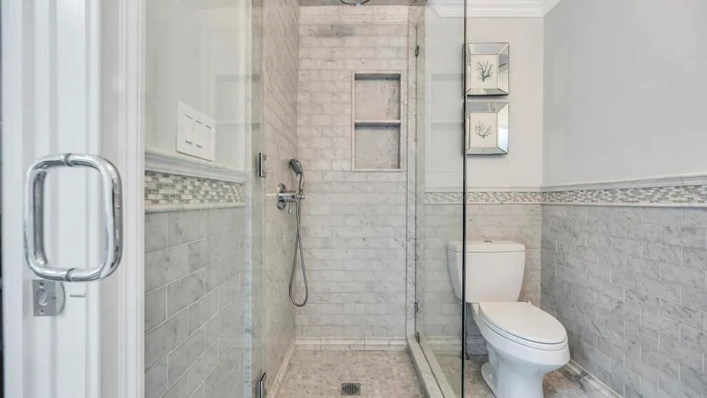 A tiled bathroom with a glass shower and a toilet.