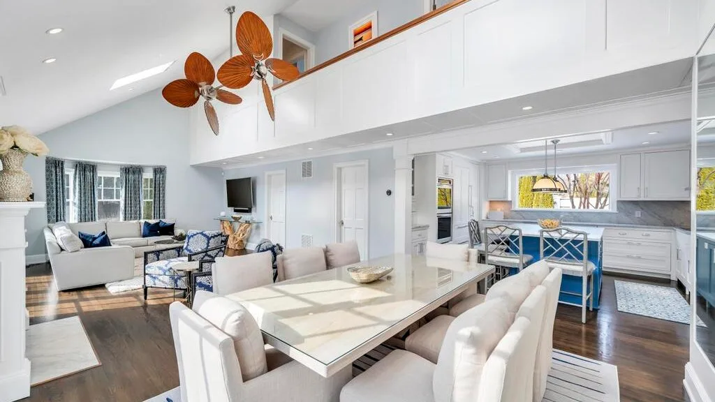 A bright open-plan living, dining, and kitchen area with a long dining table.