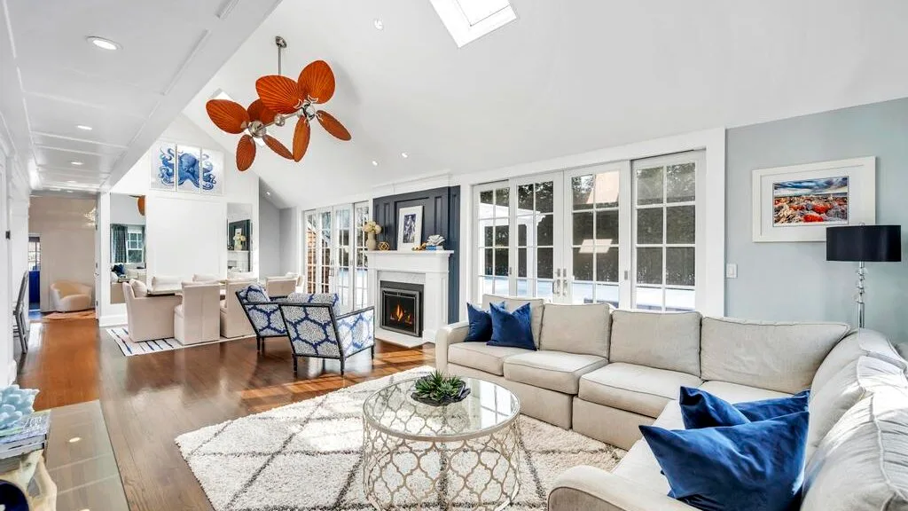 A bright living room with seating around a glass coffee table and a fireplace.
