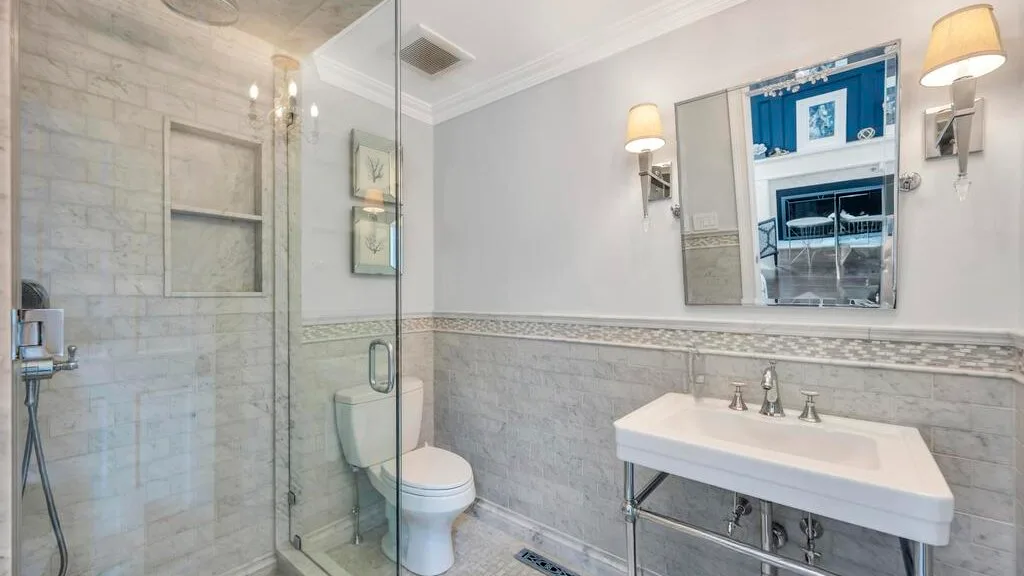 A bathroom with a glass shower, toilet, and sink.