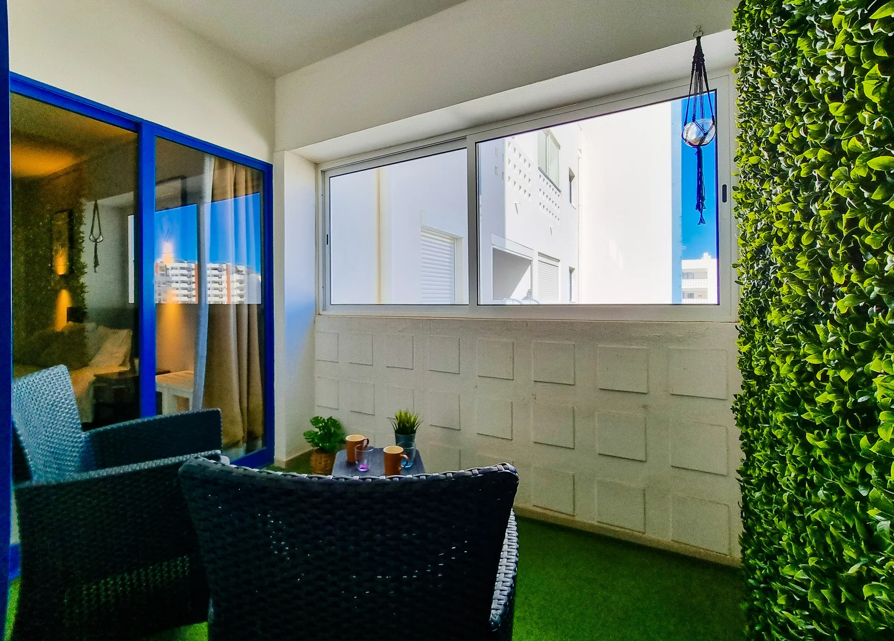 A balcony seating area with a small table and a view through the windows.
