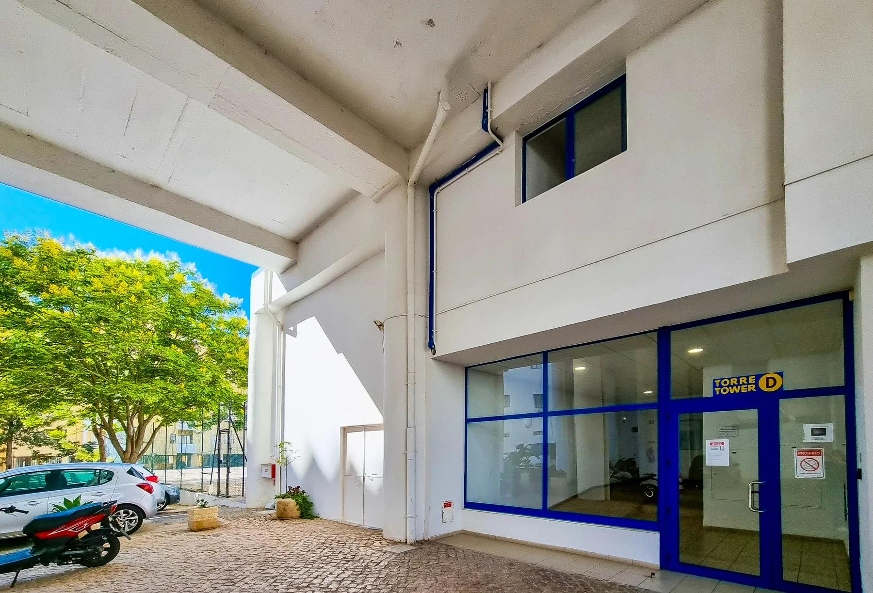 A covered building entrance with blue-framed glass doors and windows.