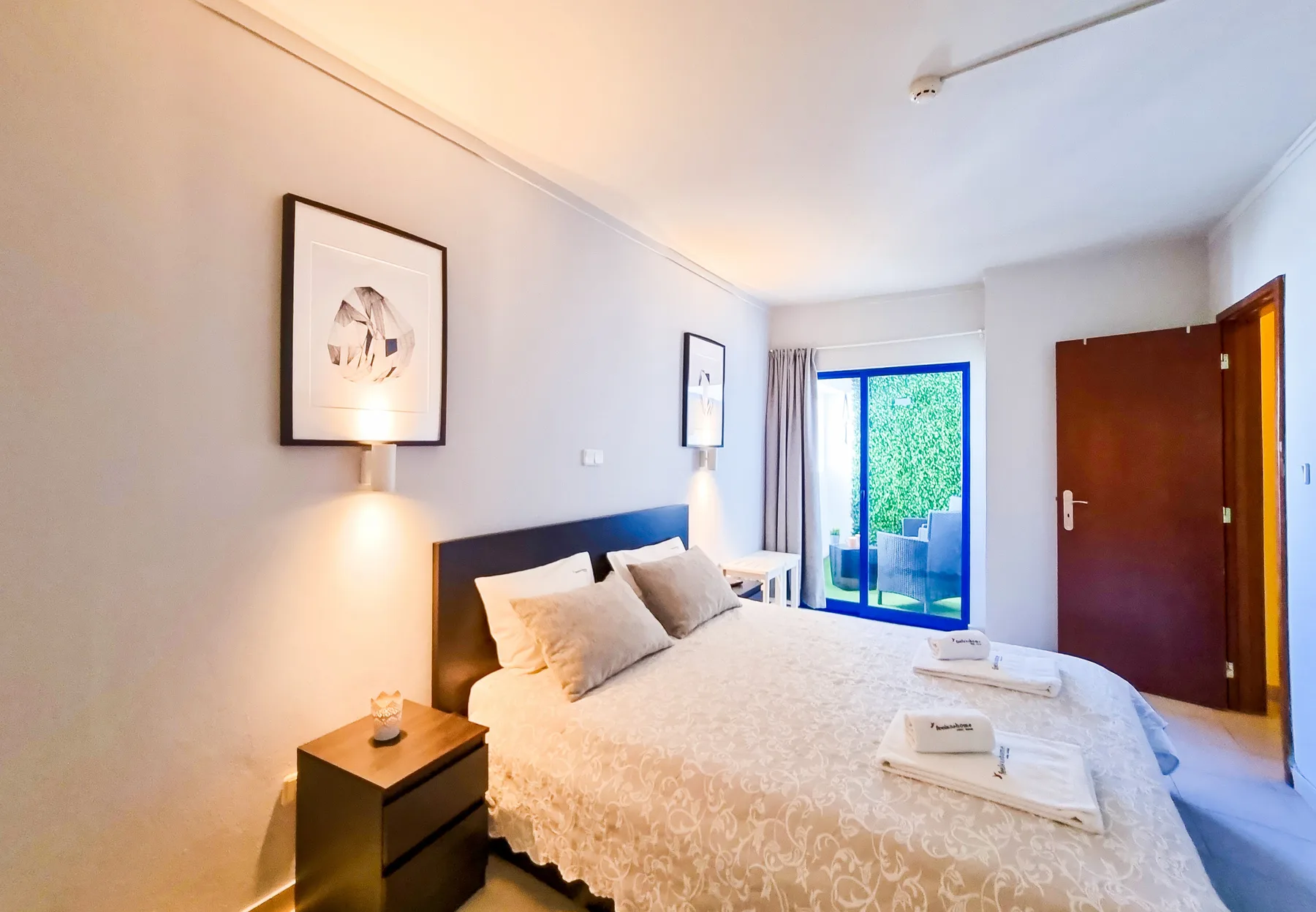 A bright bedroom with a double bed and sliding glass doors.