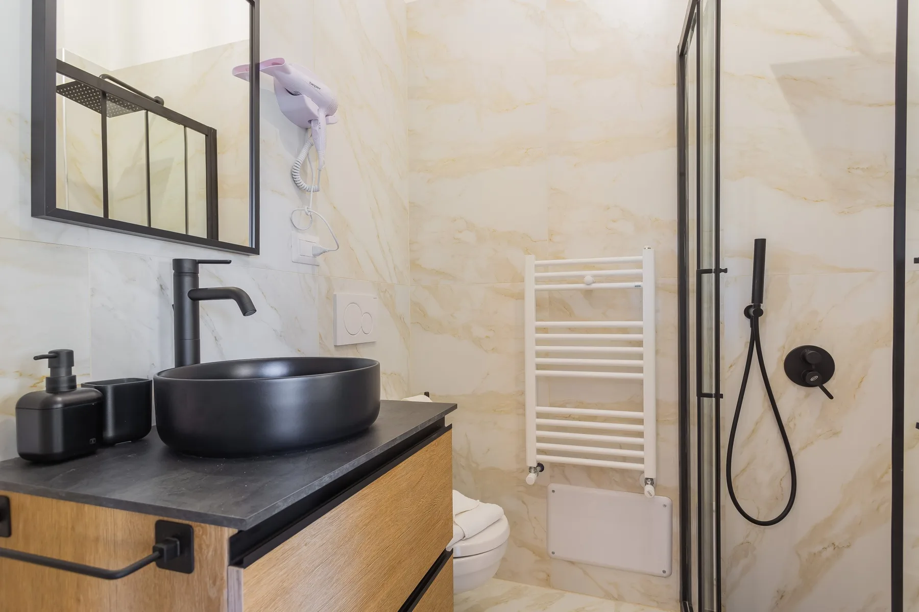 A bathroom with a vessel sink, towel warmer, and glass shower.