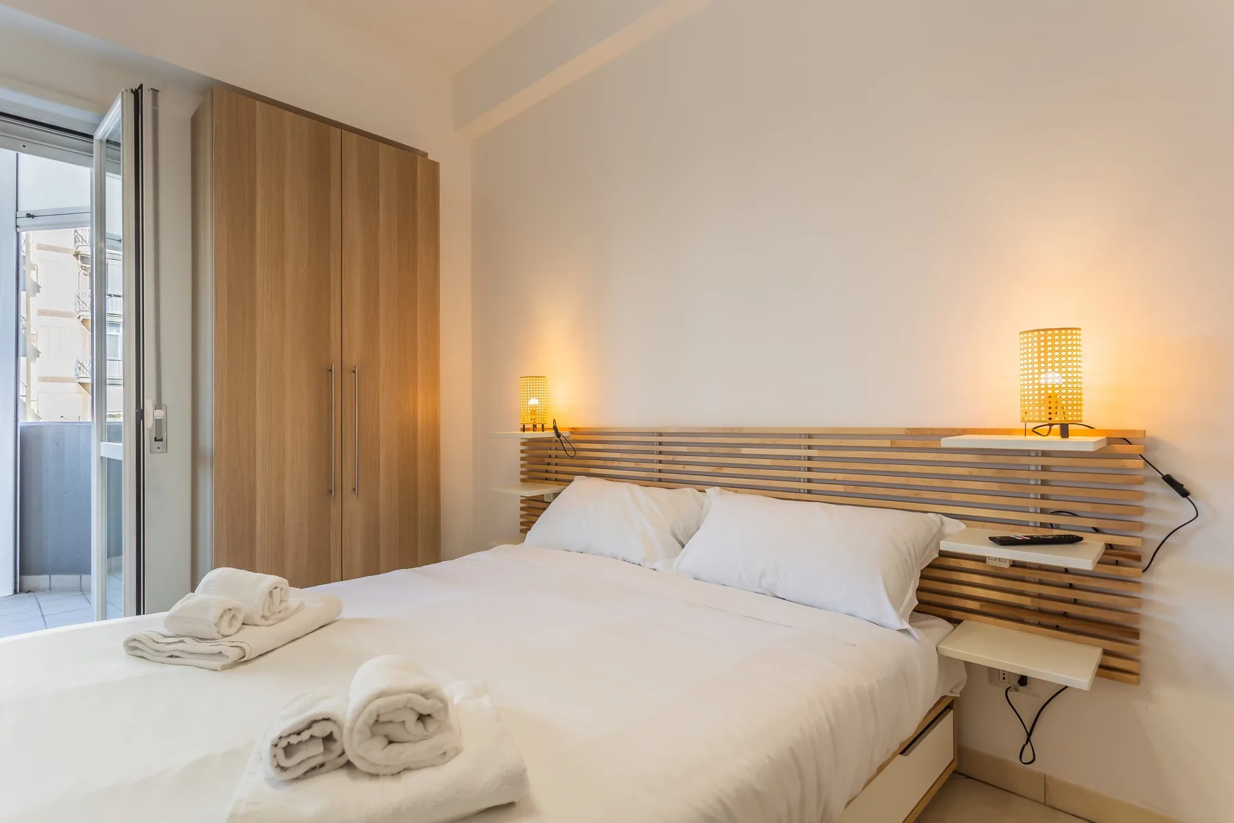 A bedroom with a neatly made bed and wooden headboard.