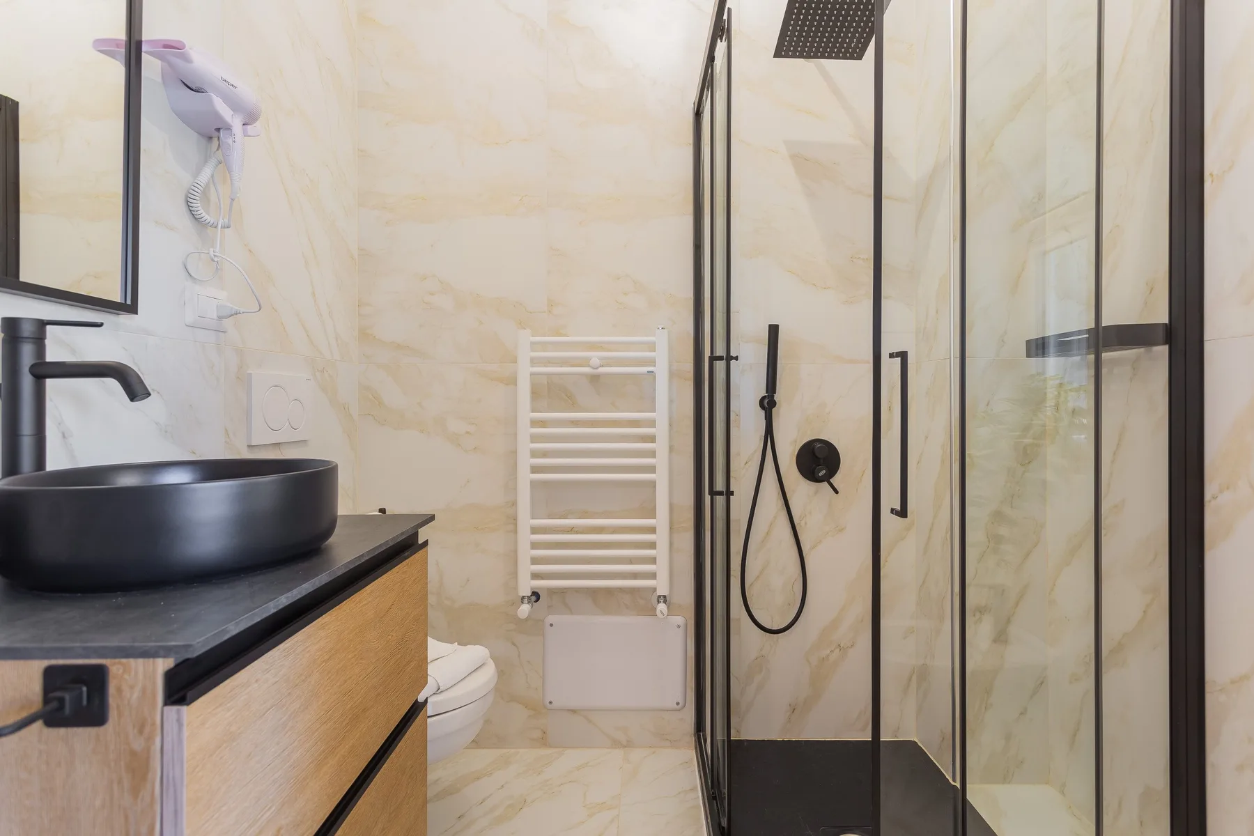 A bathroom with a glass shower, a vessel sink, and a wall-mounted towel rack.