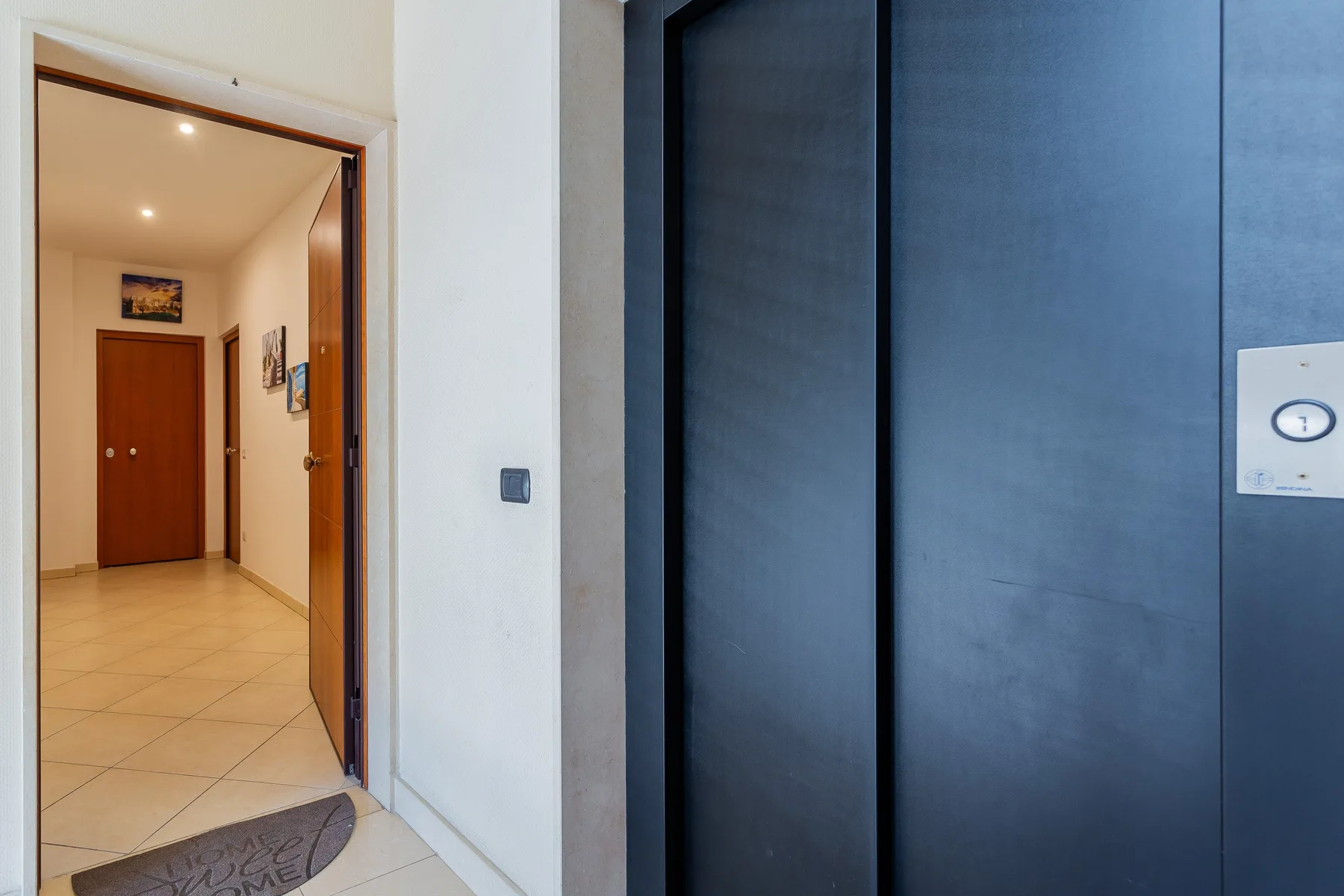 An interior entryway with a tiled floor and an open wooden doorway.