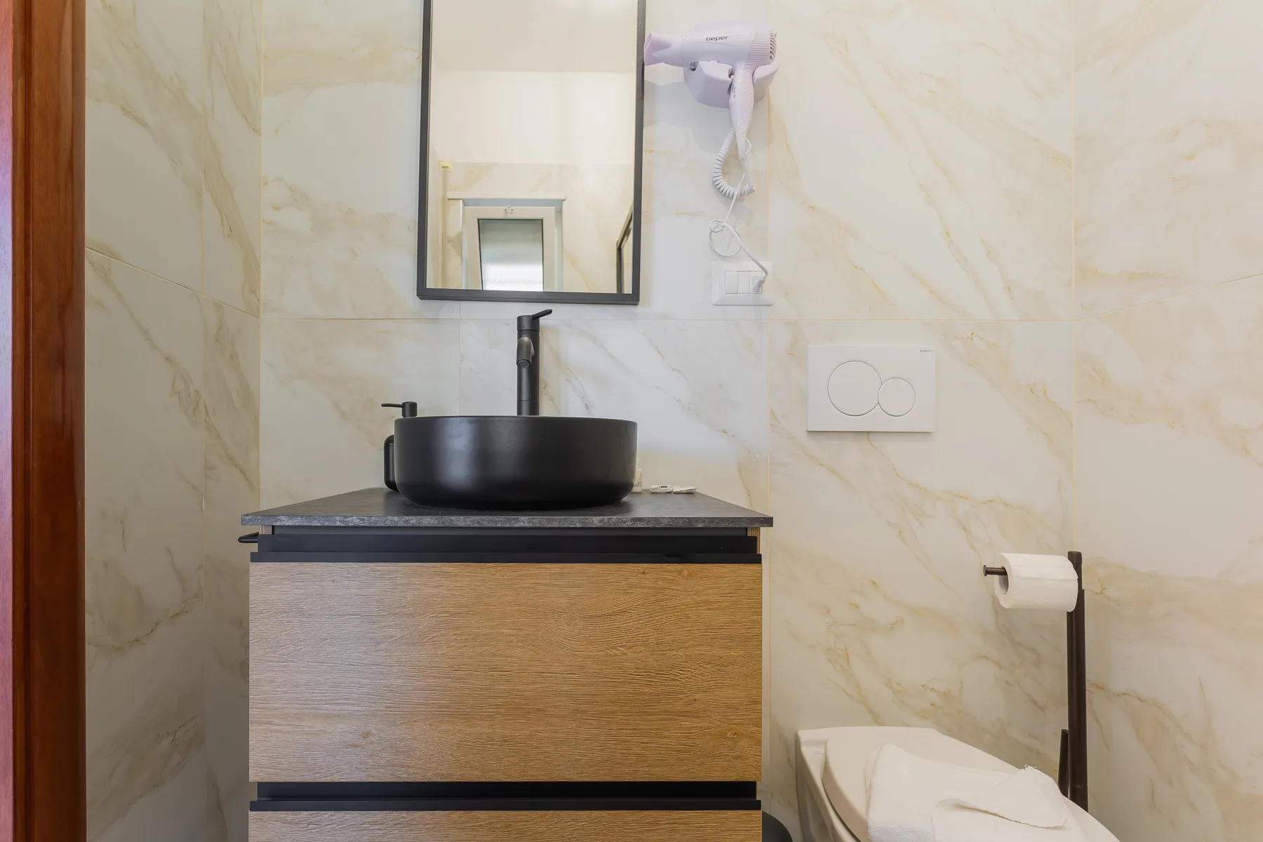 A bathroom vanity with a vessel sink, mirror, and toilet.