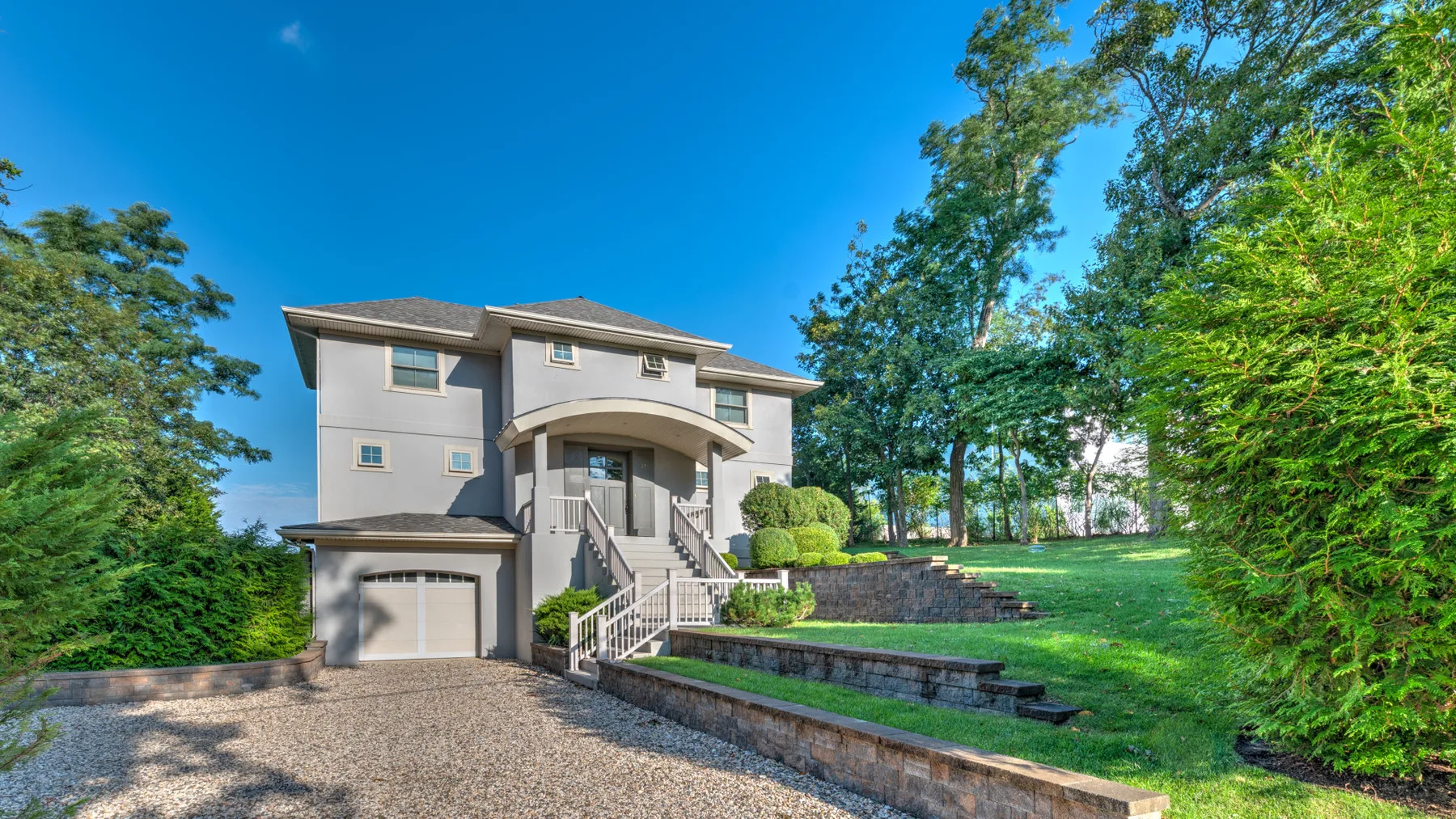 A large house stands beside a landscaped lawn and driveway.