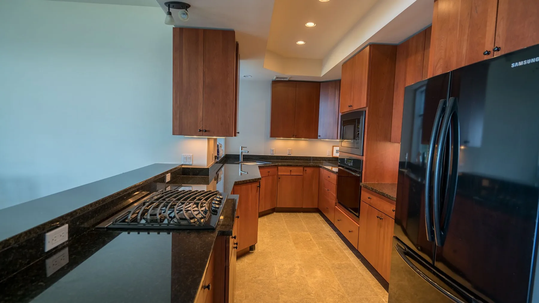 A kitchen with wooden cabinets, dark countertops, and a large refrigerator.