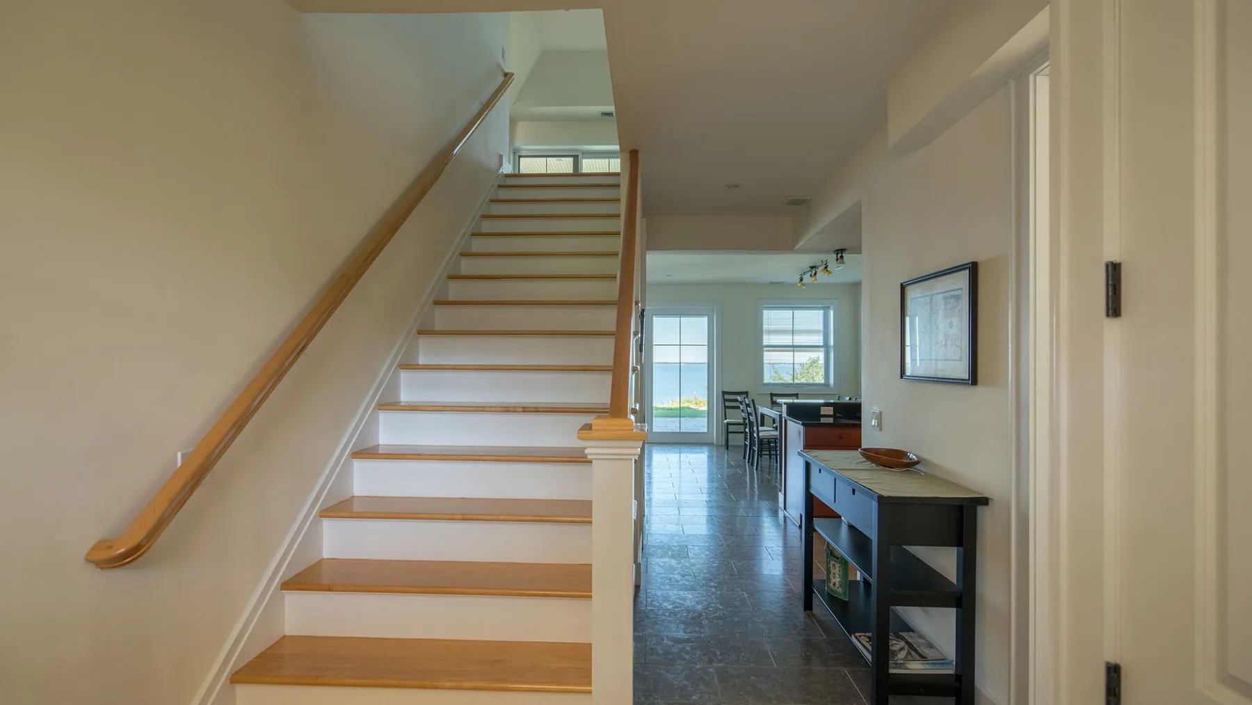 A staircase leads toward a dining area with a table and chairs.