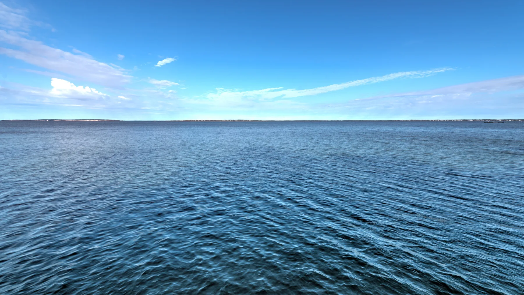 A wide expanse of water stretches beneath a blue sky.