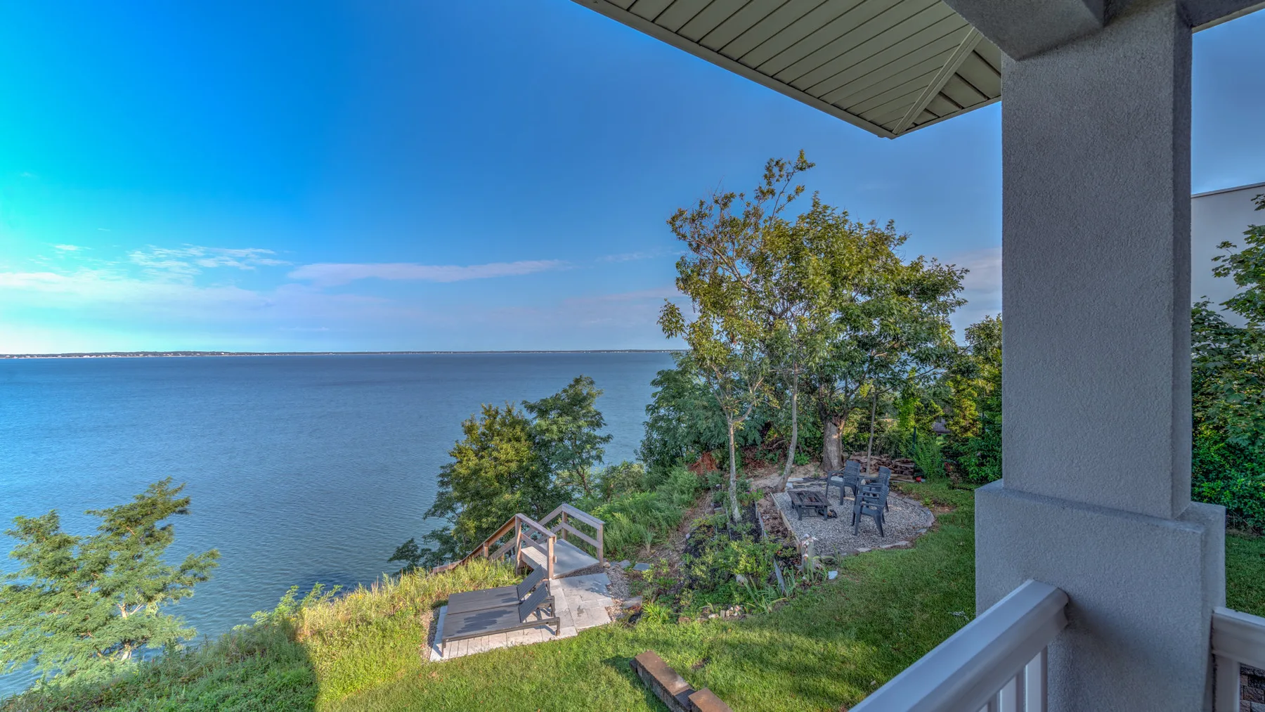 A waterfront patio overlooks the water, with outdoor seating among the trees.