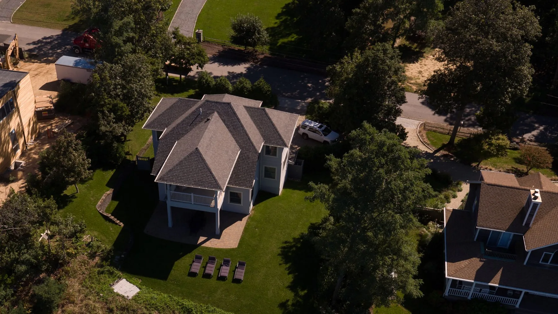 An aerial view of a house surrounded by trees and green lawn.