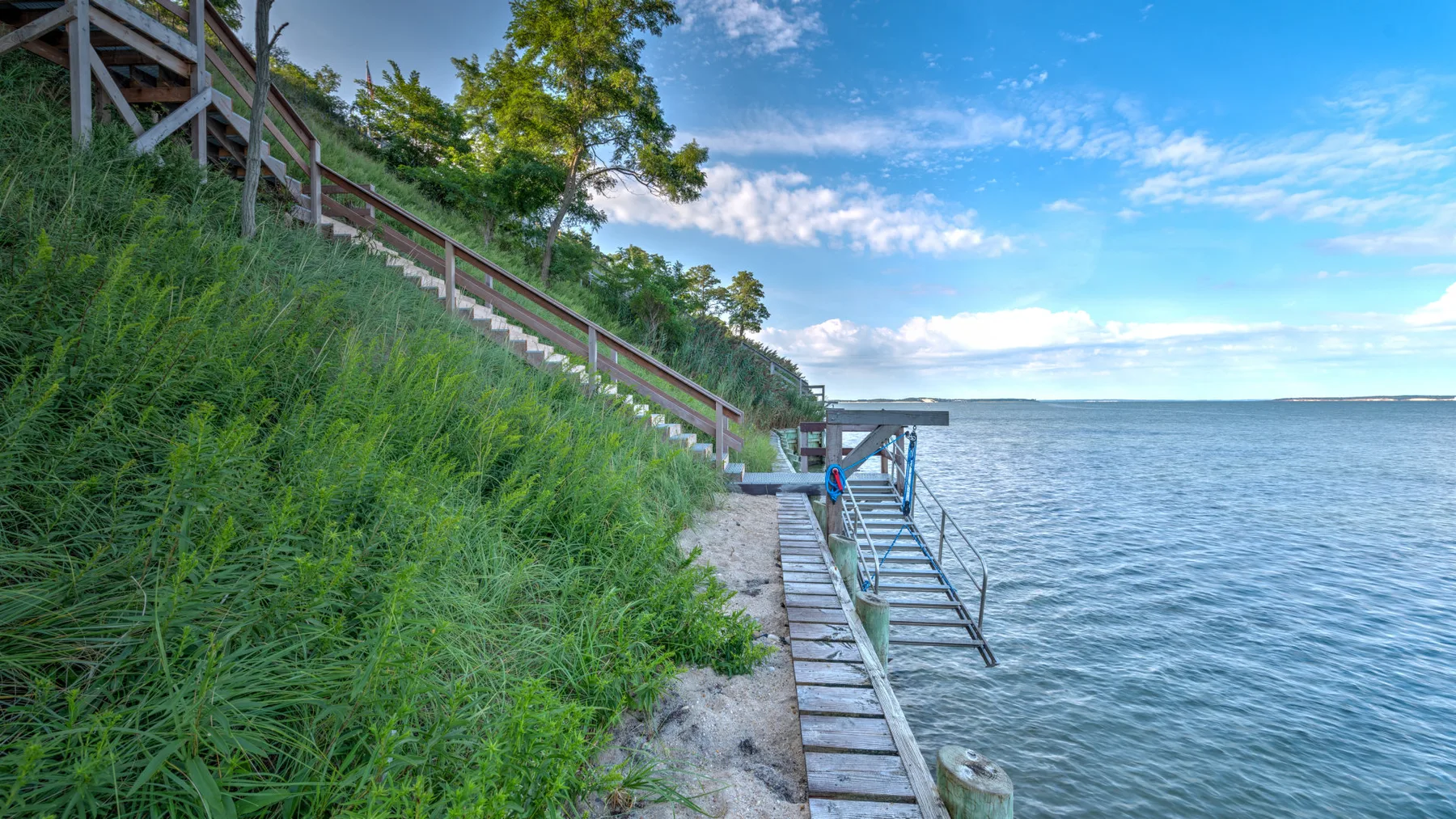 A lakeside landing with a wooden walkway and metal stairs beside the water.