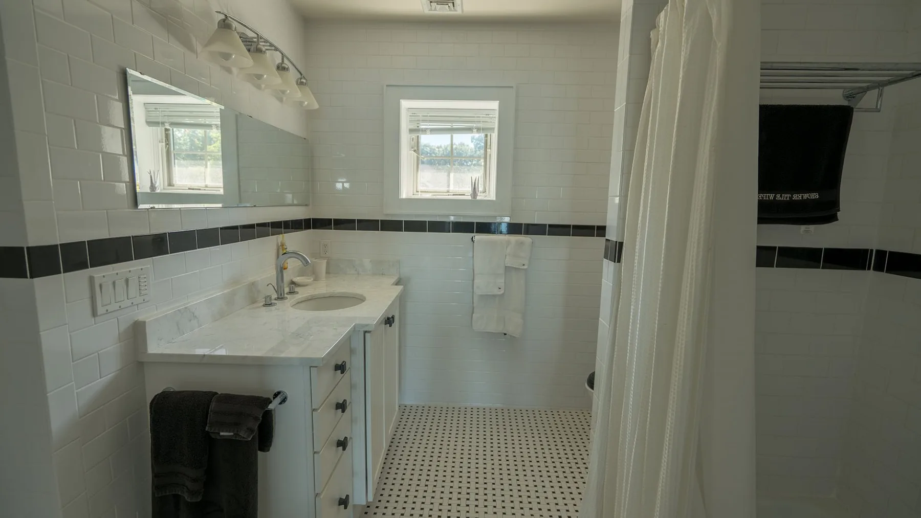 A tiled bathroom with a sink vanity, window, and shower curtain.