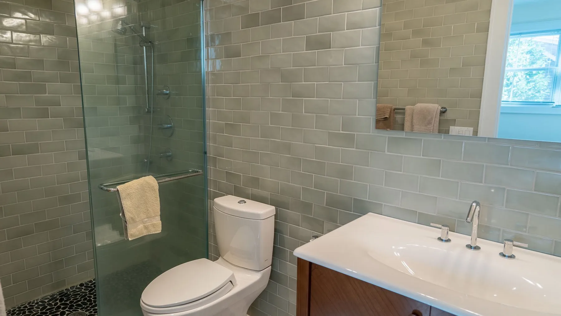 A tiled bathroom with a glass shower and a sink vanity.