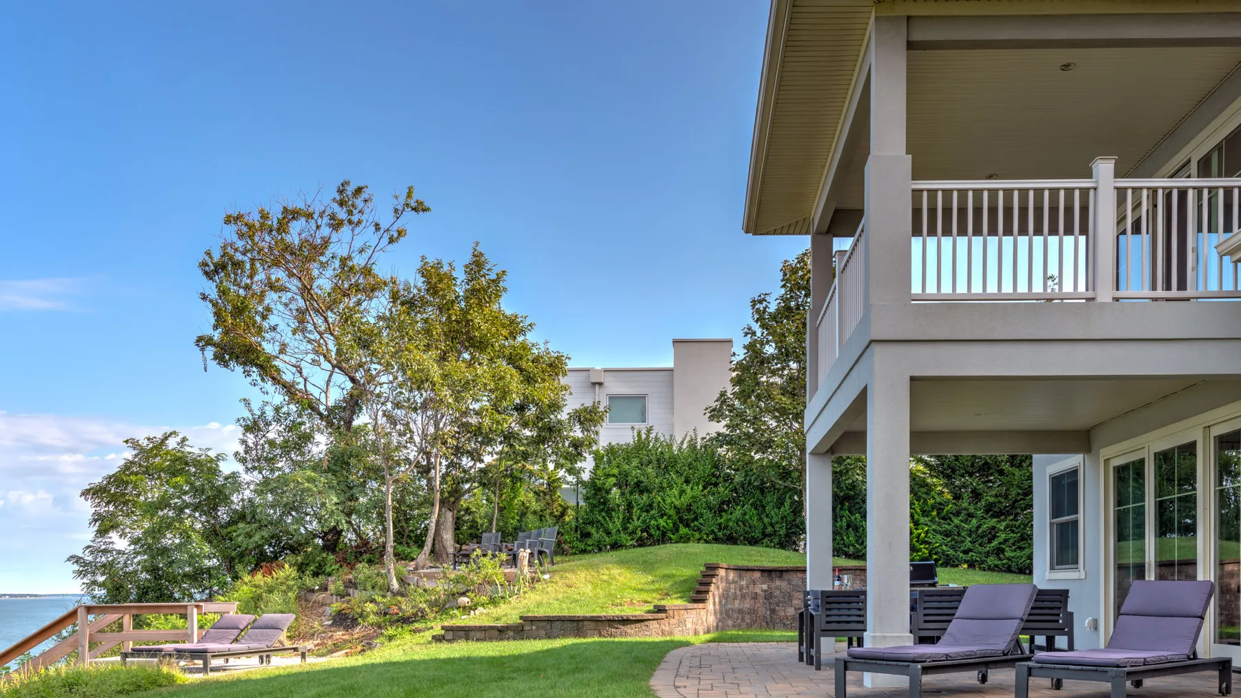 A landscaped outdoor patio beside a modern house, with seating and a tree.