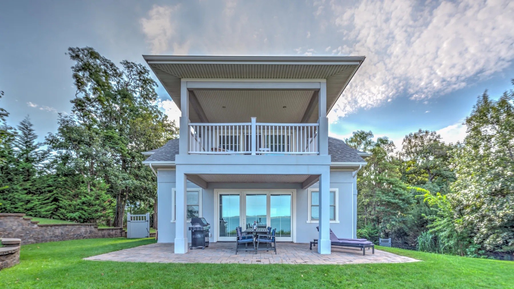 A two-story house with a covered upper balcony and sliding glass doors.
