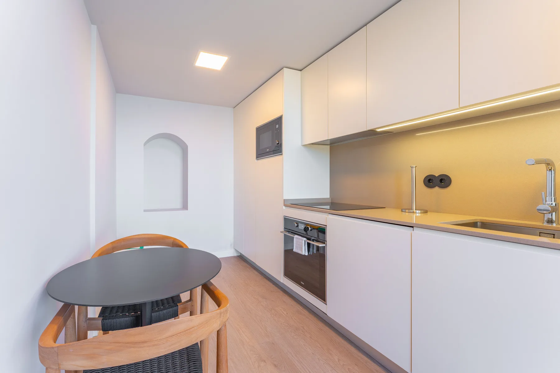 A compact kitchen and dining area with a round table and built-in appliances.