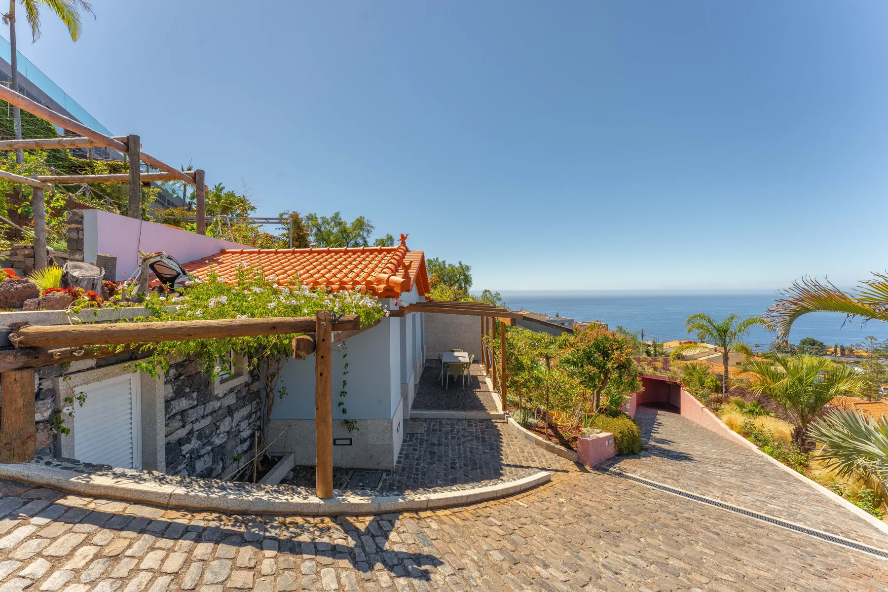 A garden terrace with a paved path overlooks the sea.