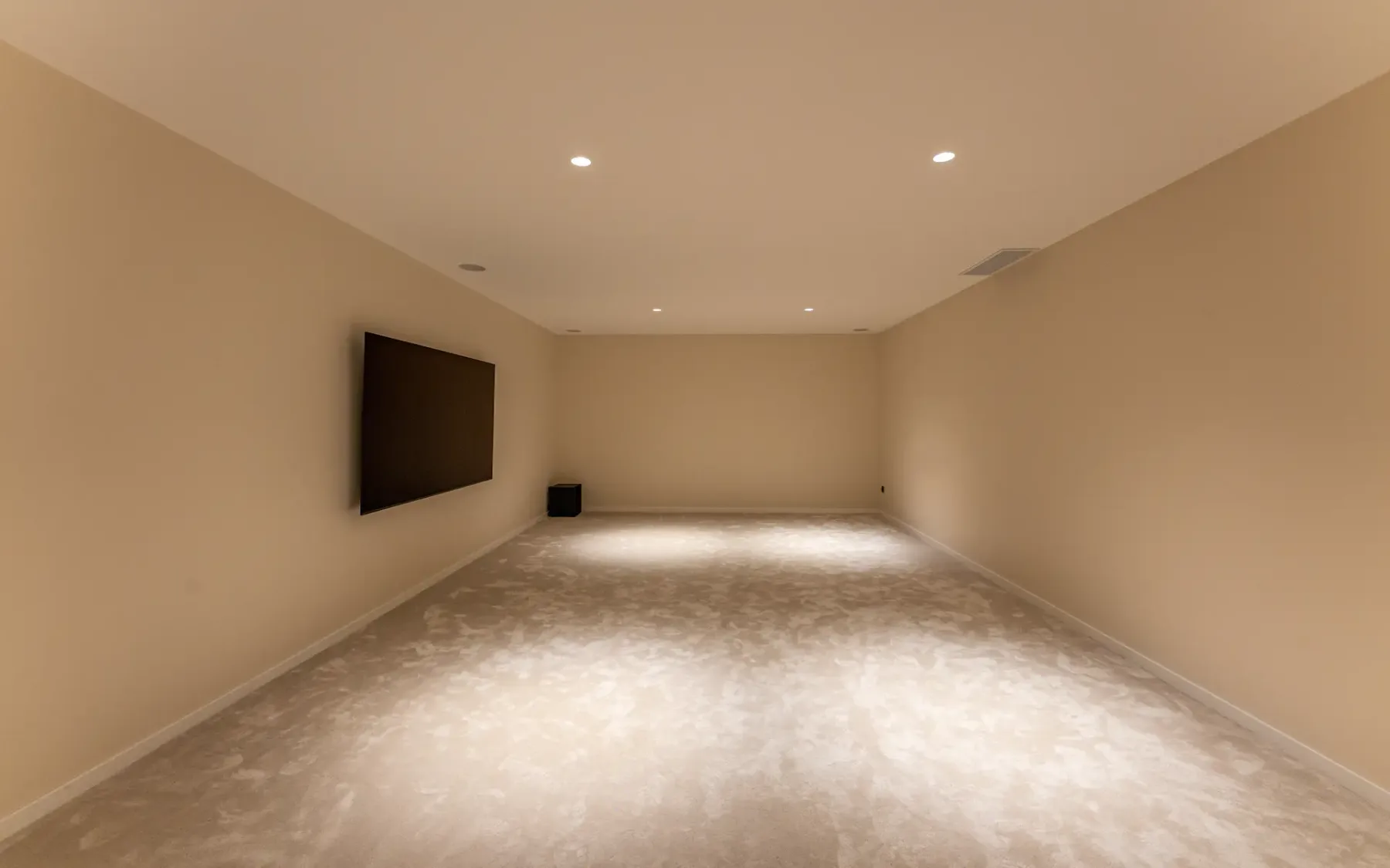 Habitación vacía, amplia y diáfana con un televisor de pantalla plana montado en la pared.