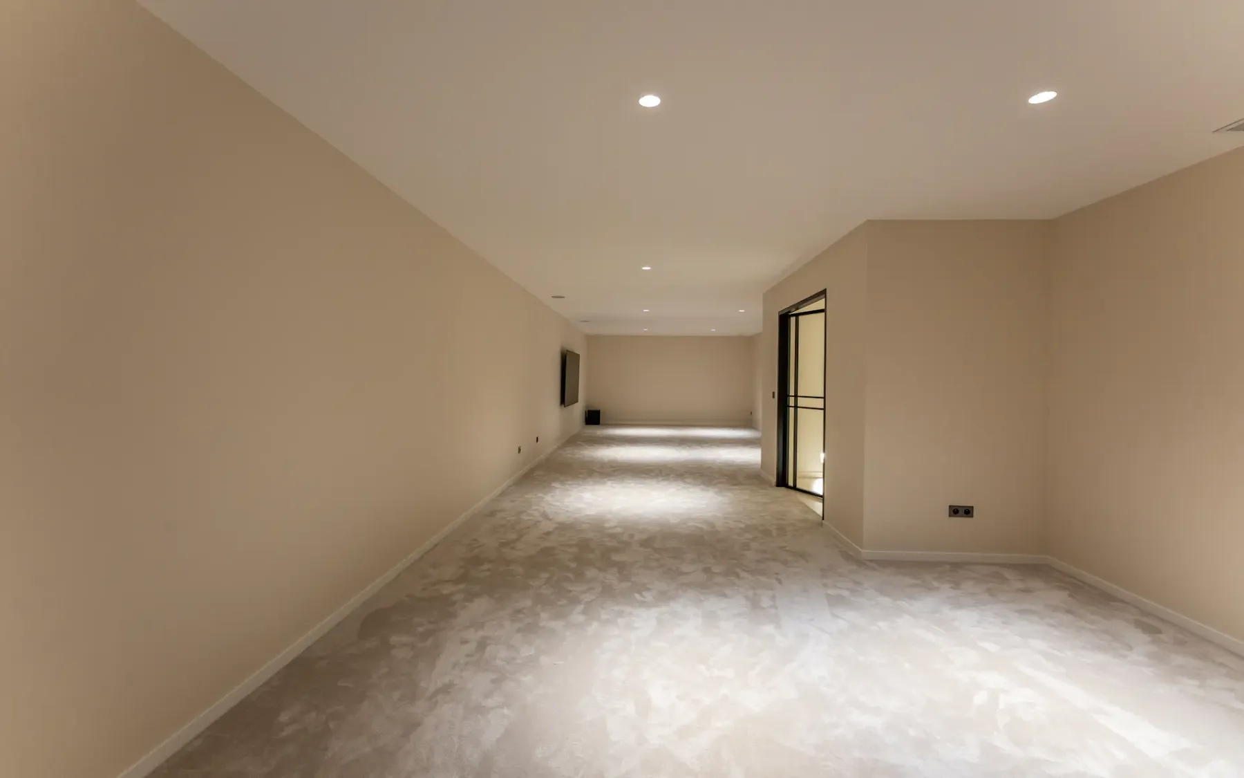 Habitación vacía y muy amplia, con suelo de moqueta y una puerta abierta.