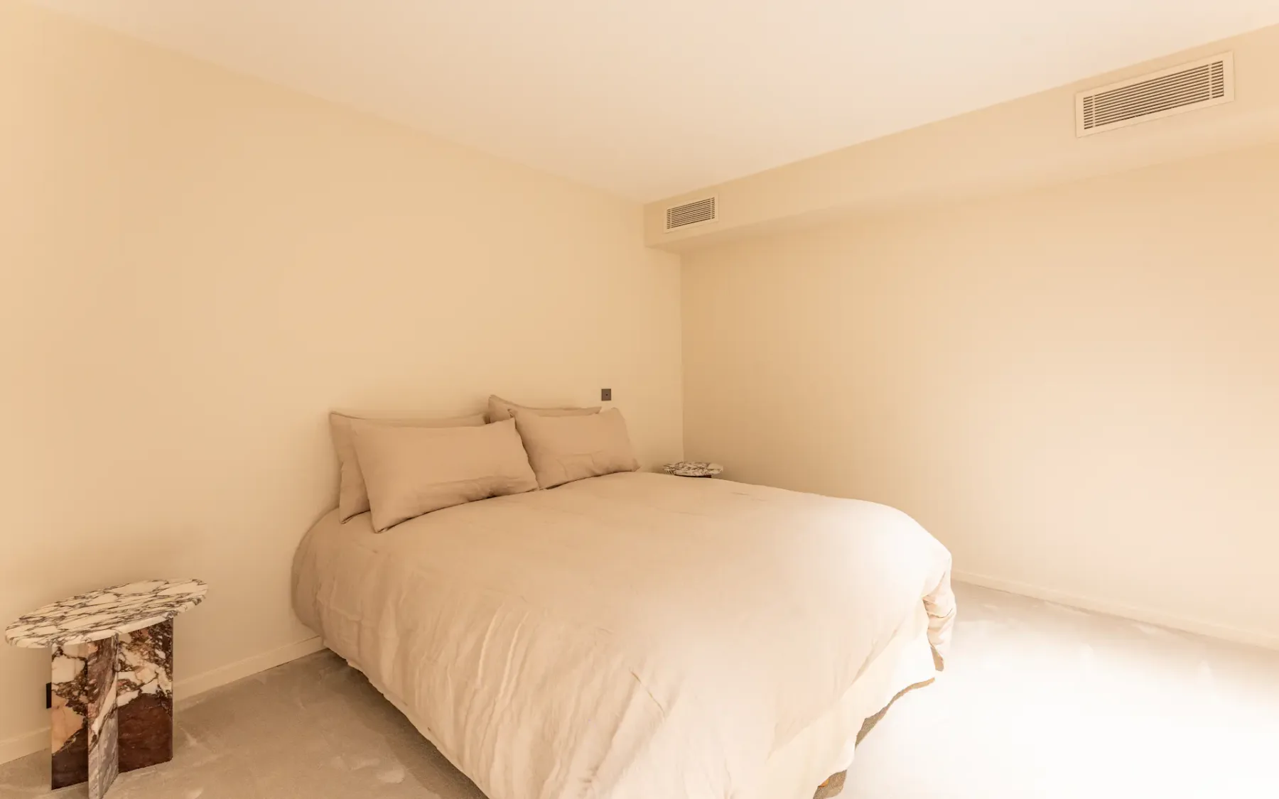 Dormitorio blanco sencillo y limpio con una cama doble y una mesa de noche contemporánea.