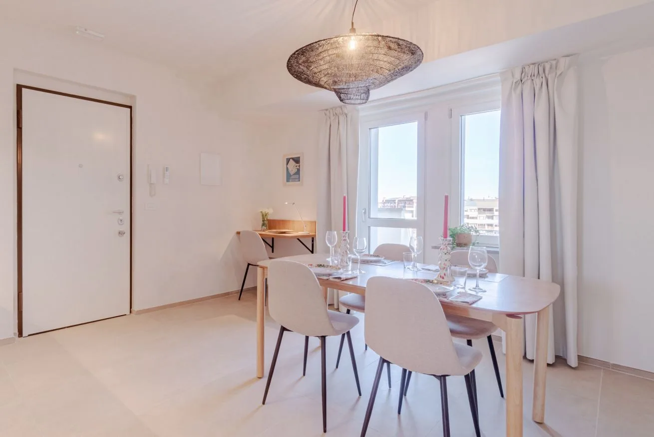 Comedor con una mesa de madera y sillas junto a grandes ventanas.