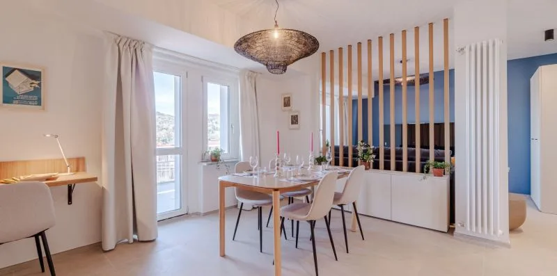 Un comedor luminoso con una mesa puesta, una lámpara colgante y listones verticales de madera.
