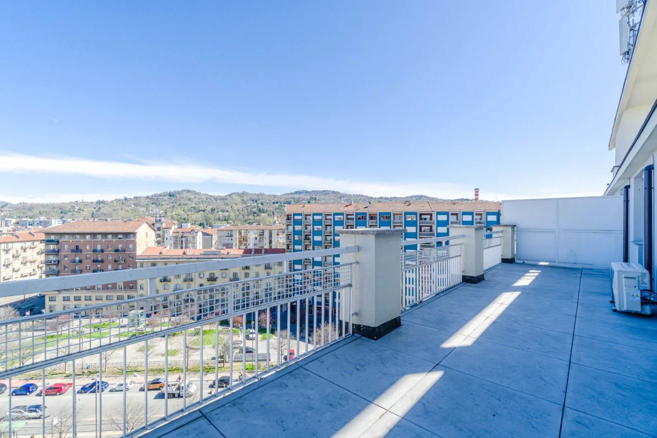 Una amplia terraza en la azotea con barandillas metálicas y vistas a edificios cercanos.