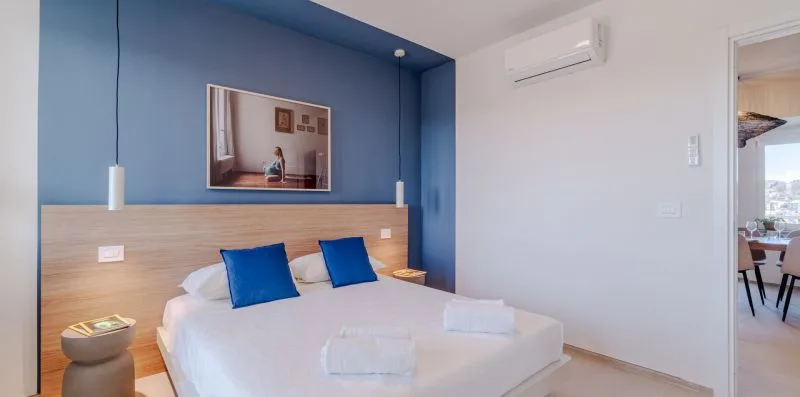 Un dormitorio con una cama, una pared azul y un cuadro enmarcado.