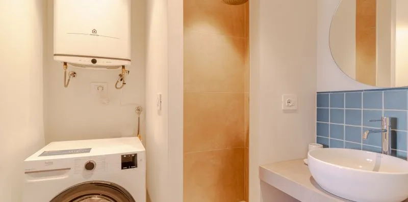 Un baño compacto con una lavadora y un lavabo blanco.