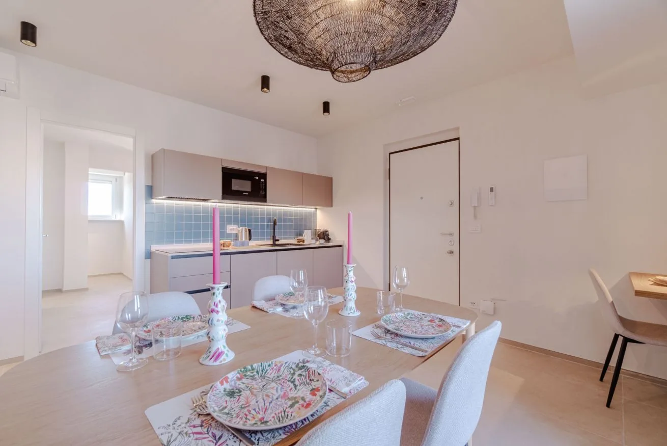 Un comedor con la mesa puesta está junto a una cocina compacta.