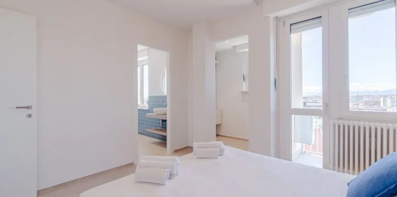 Un dormitorio luminoso con una cama, ventanales y un radiador.