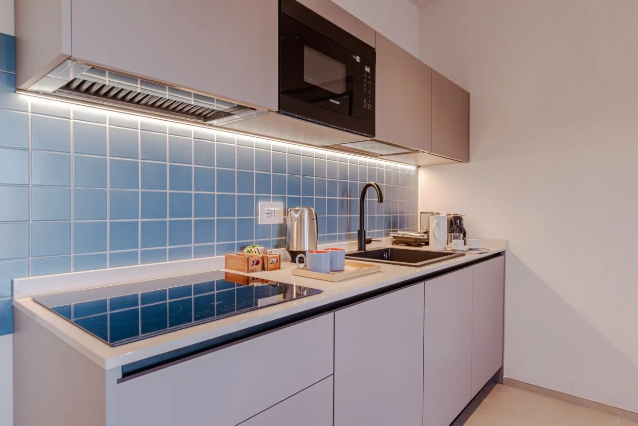 Una cocina moderna con salpicadero de azulejos azules y una placa de cocina.