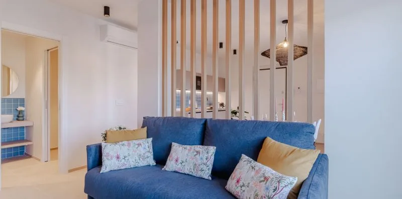 Un sofá azul está junto a una celosía de listones de madera en una sala luminosa.