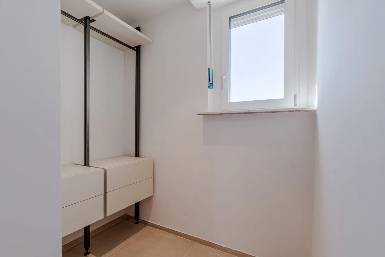 Un vestidor luminoso con cajones empotrados y una ventana.