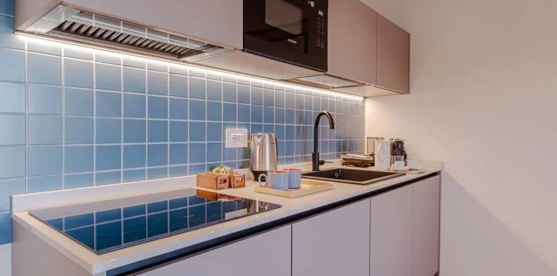Una encimera de cocina moderna con fregadero, placa de cocción y azulejos azules.