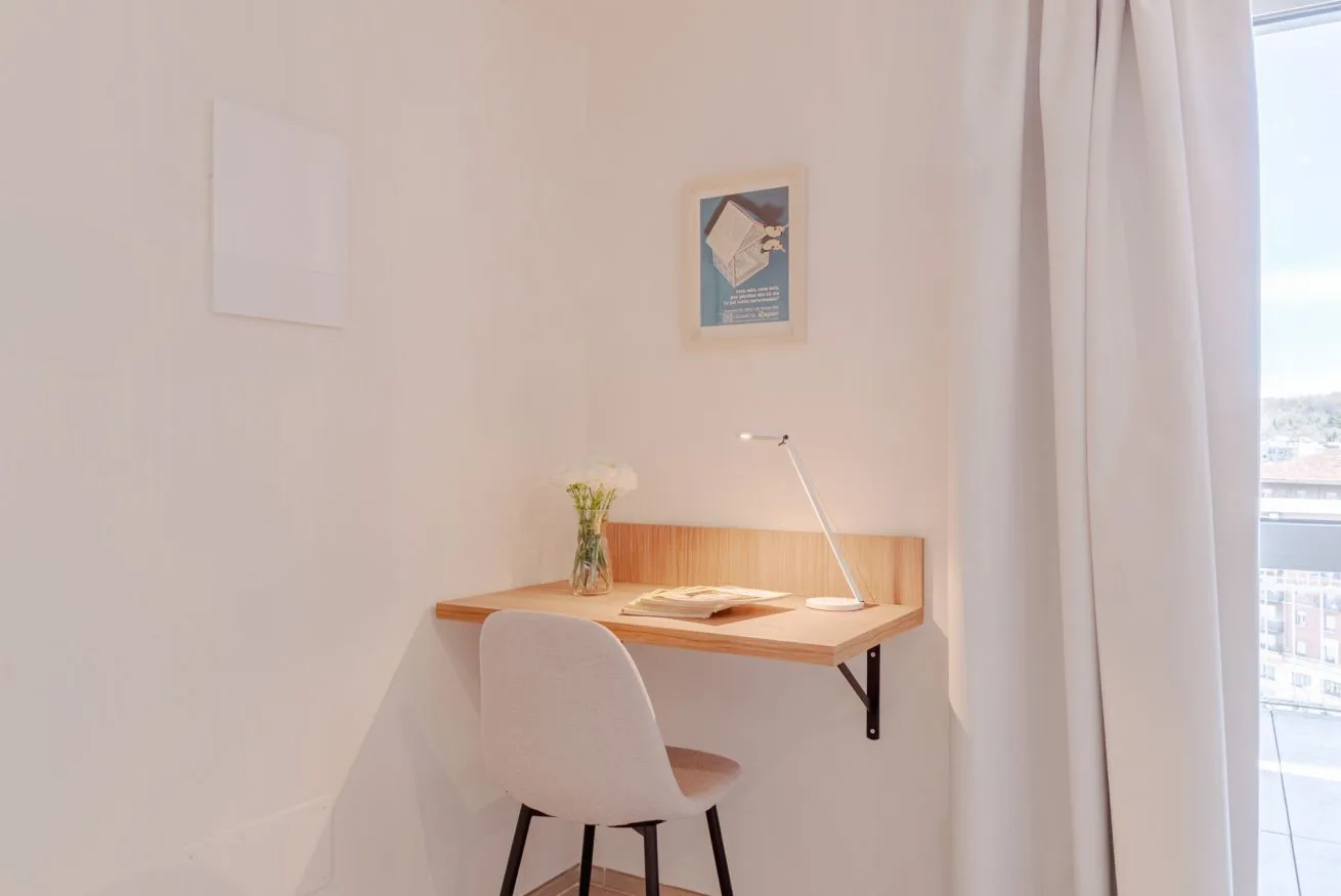Un rincón de escritorio luminoso con una silla junto a una ventana grande.