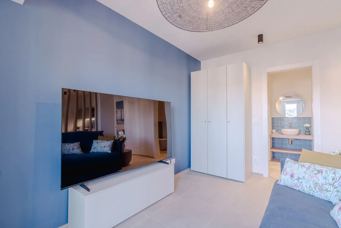 Un dormitorio con un televisor en la pared y una puerta hacia un baño.
