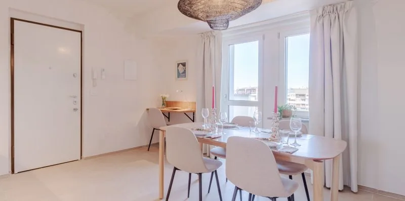 Un comedor luminoso con una mesa y sillas junto a grandes ventanas.