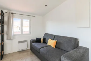 Una sala luminosa con asientos grises y una ventana.