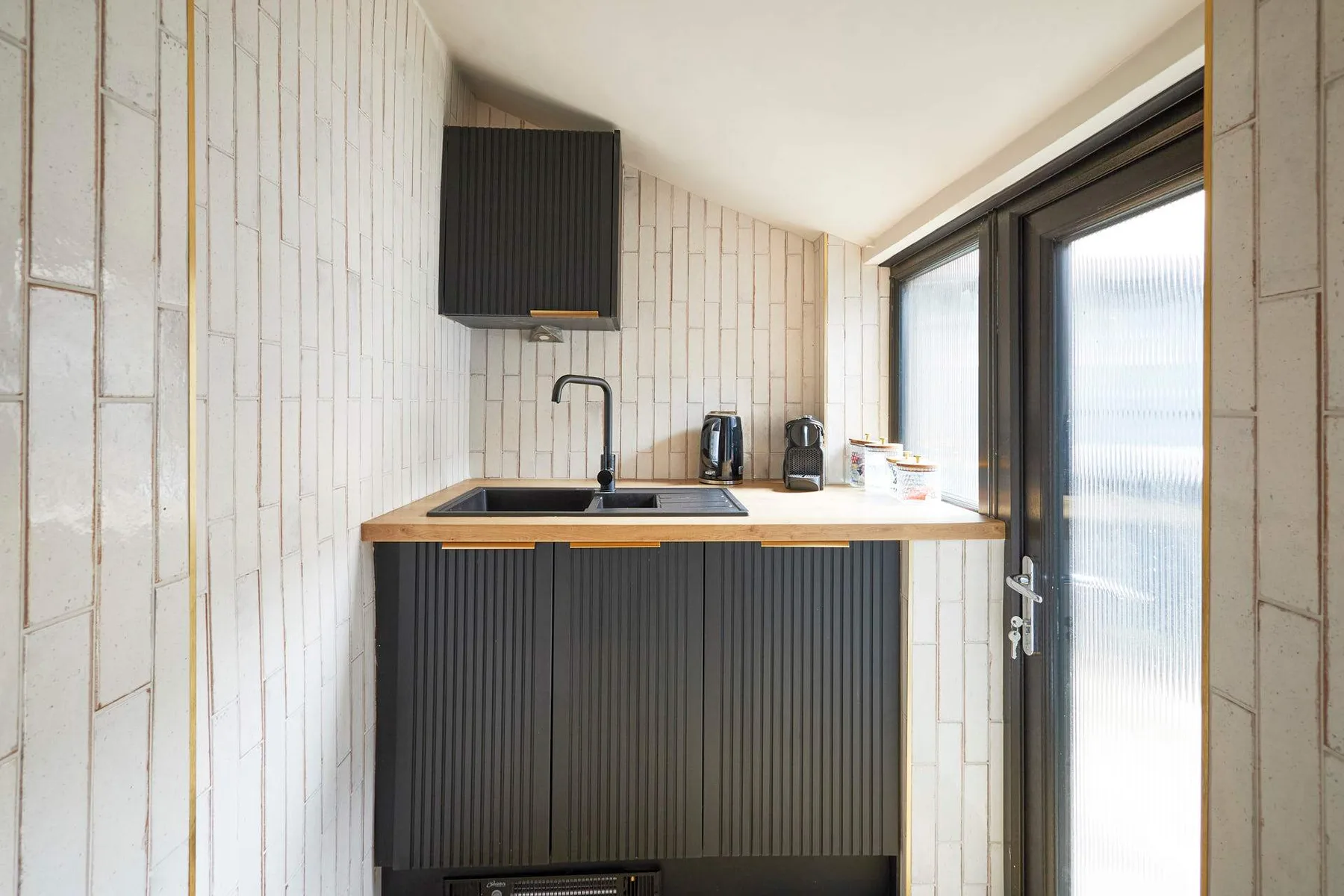 A compact kitchen with dark cabinets and a countertop beside a glass door.