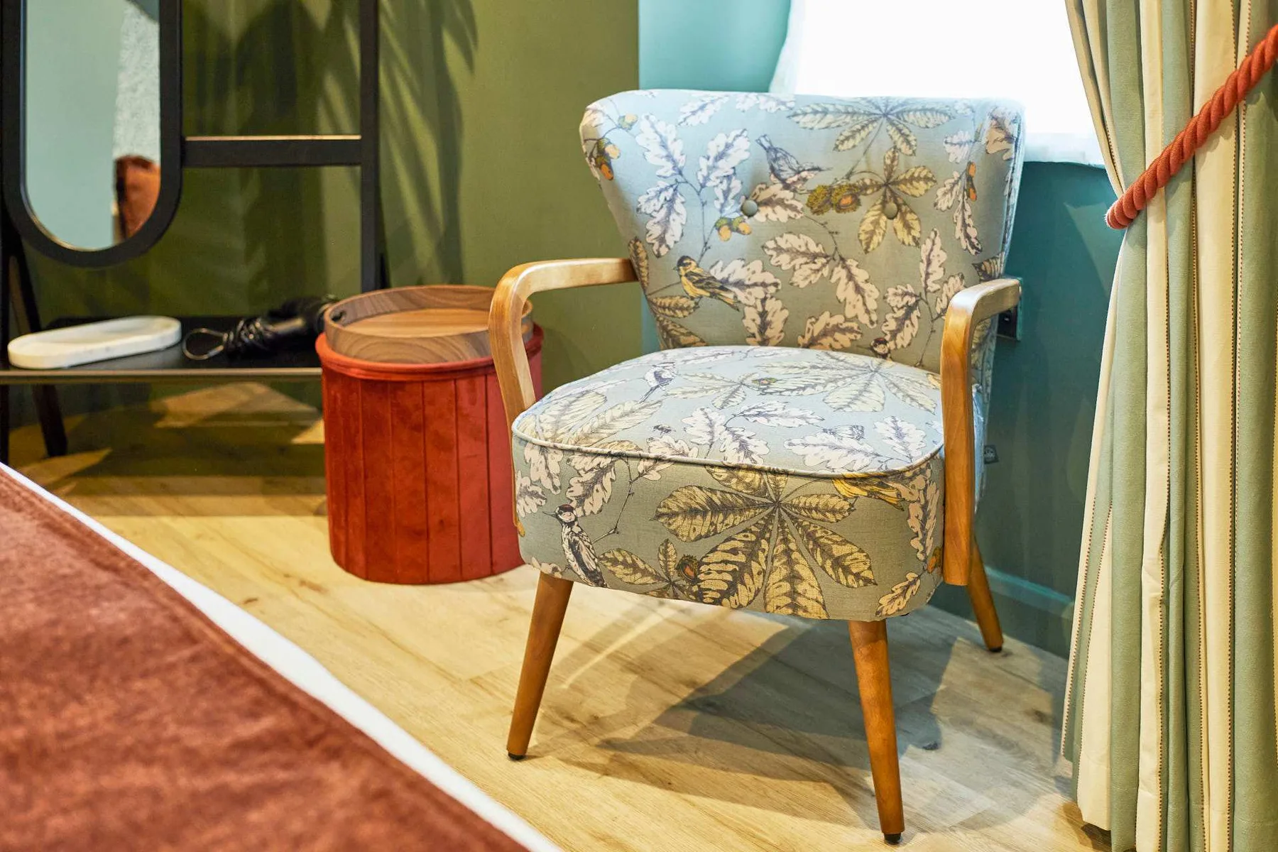 A patterned upholstered chair sits beside a small round wooden table.