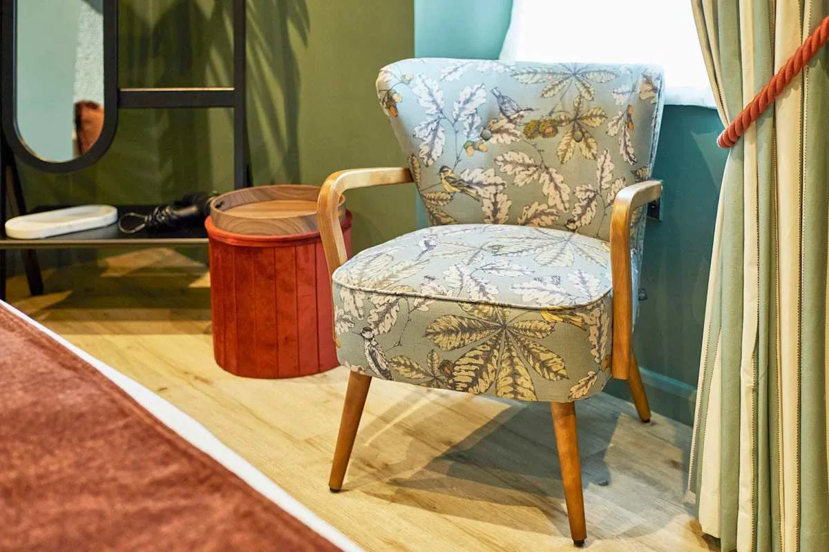 A patterned armchair sits beside a small wooden table in a sitting area.
