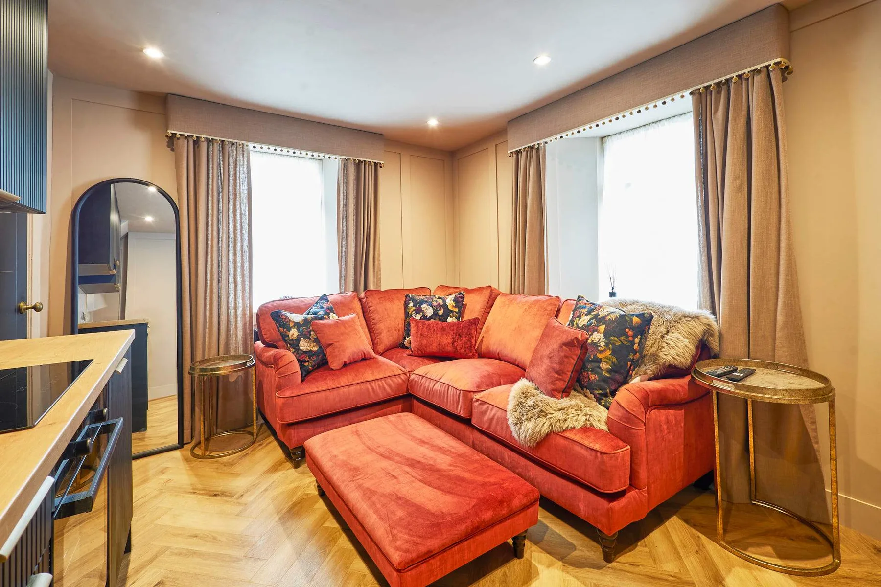 A living room with a red sectional and matching ottoman.